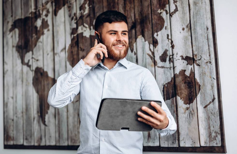 Handsome busy businessman talking on the phone and looking at important document on tablet.